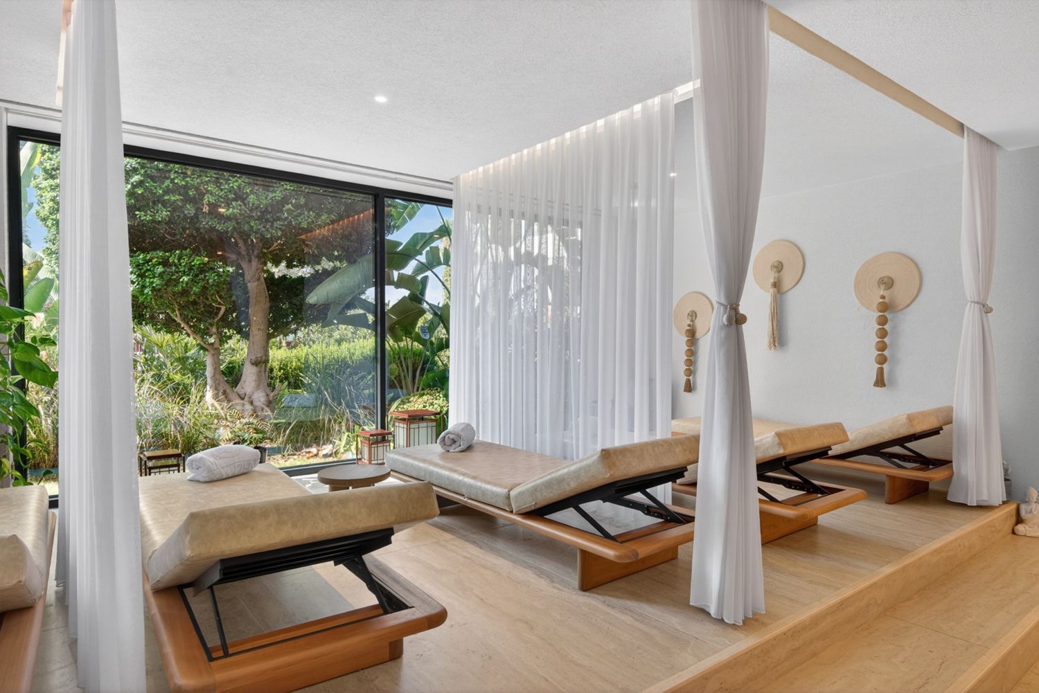 Tül perdeli, ahşap şezlonglu aydınlık bir spa dinlenme alanı